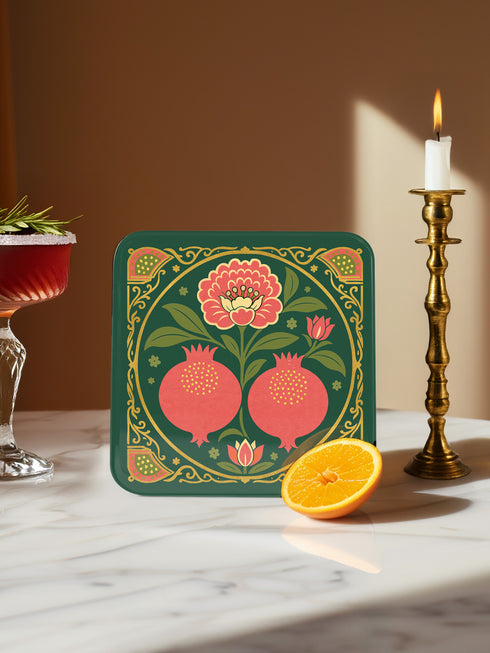 Set of four square drinking coasters featuring rich, dark green botanical illustration with highly detailed Pomegranate fruits and sliced cross-sections. The ornate pattern utilizes deep crimson, opulent gold, and ivory tones, strongly reflecting the stylized Art Nouveau period aesthetic and William Morris textile designs. Crafted from durable, resilient masonite hardboard, this luxury item features a protective high-gloss finish and a non-slip cork base.